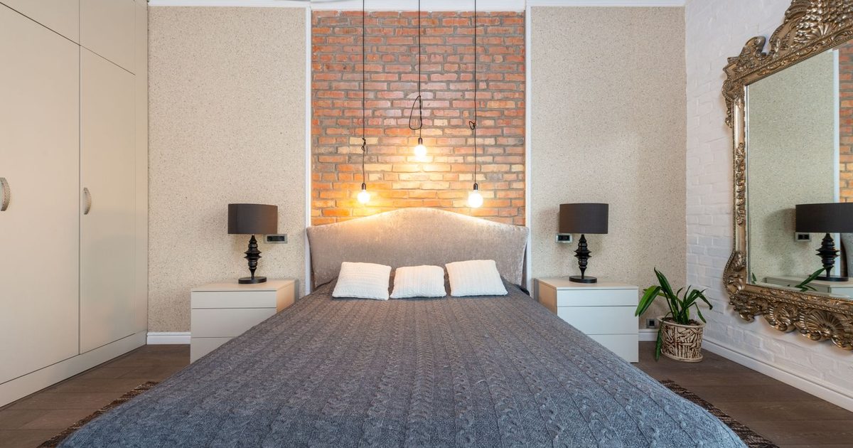 A bedroom with a brick accent wall